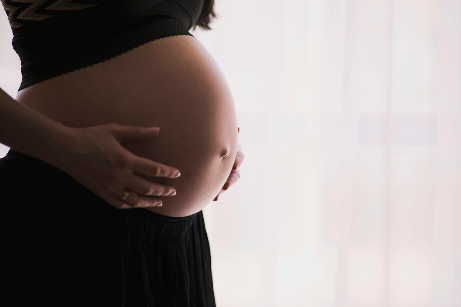 Pregnant person cradling their belly while planning birth preferences